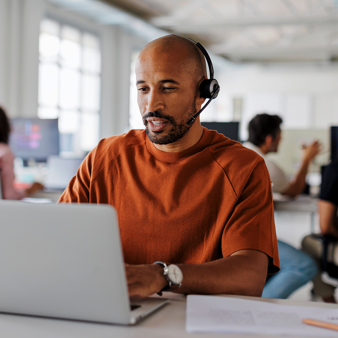 Image of a customer care representative wearing a headset at a computer