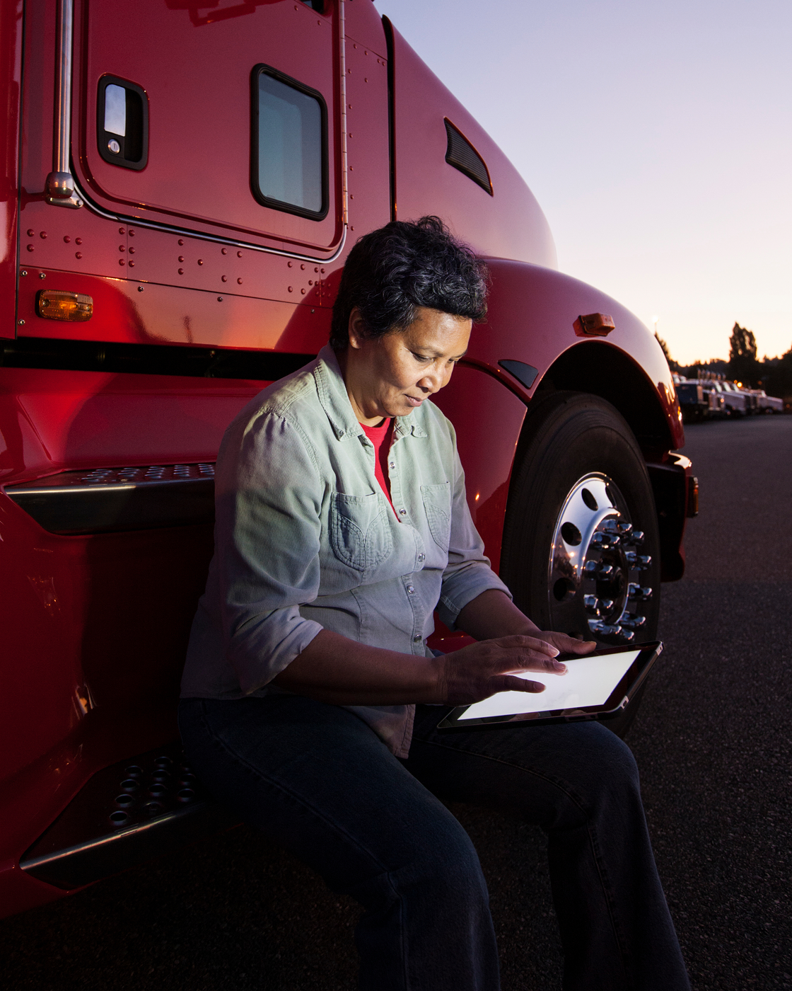 Image of a person in front of a truck using a tablet at dusk