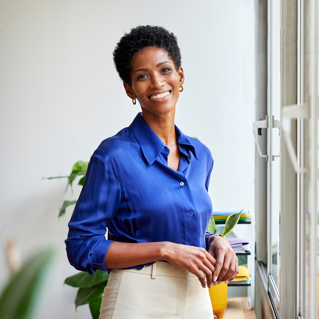 Image of woman smiling to camera in an office setting wearing a blue shirt