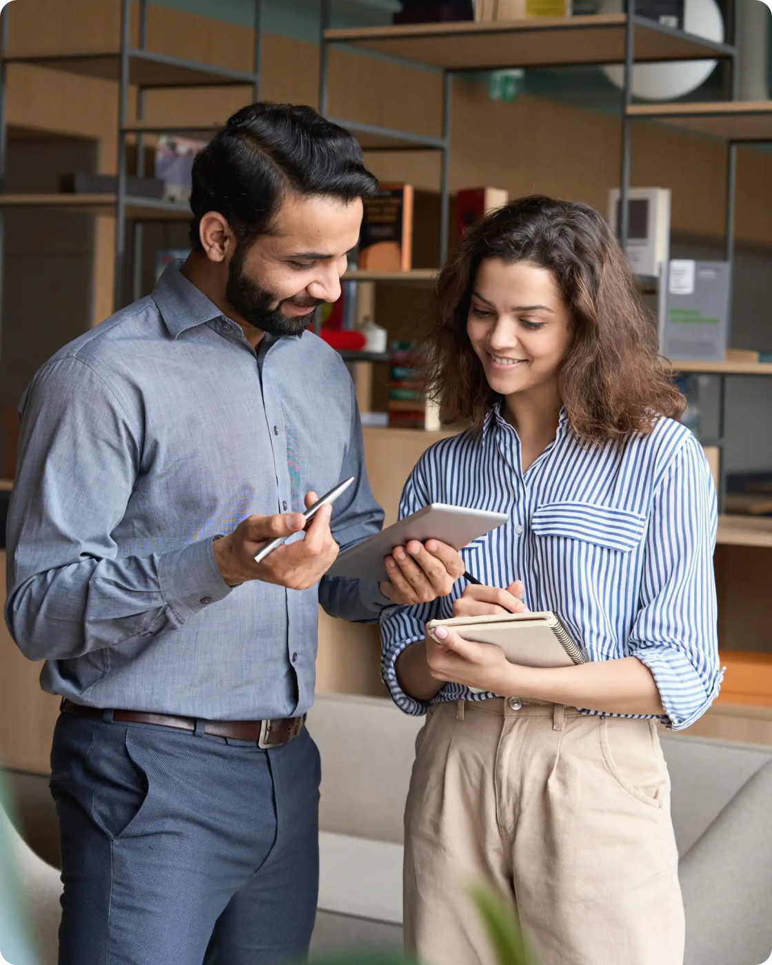 Image of two people looking at a notepad in an office setting