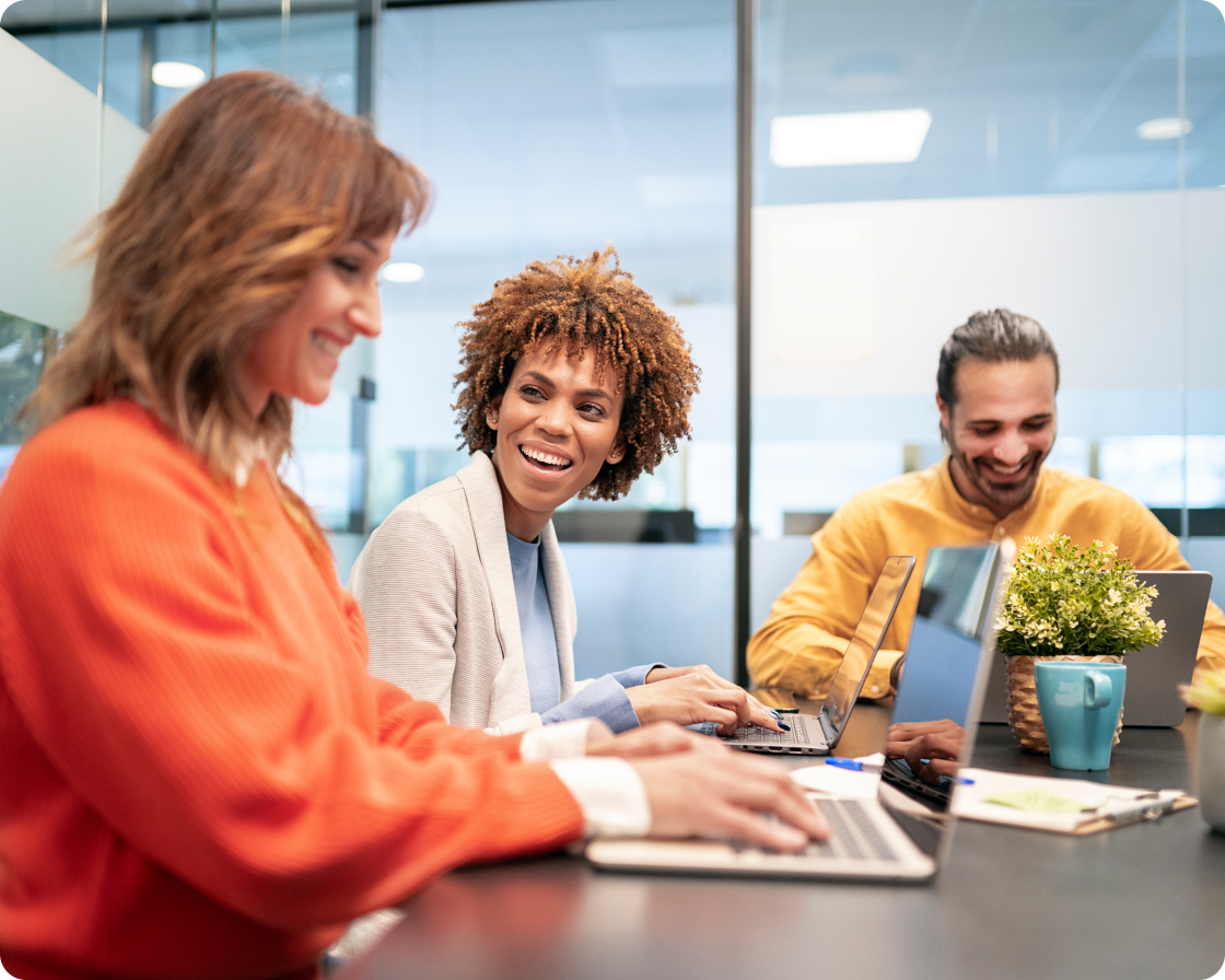 Image of coworkers laughing and typing on laptops