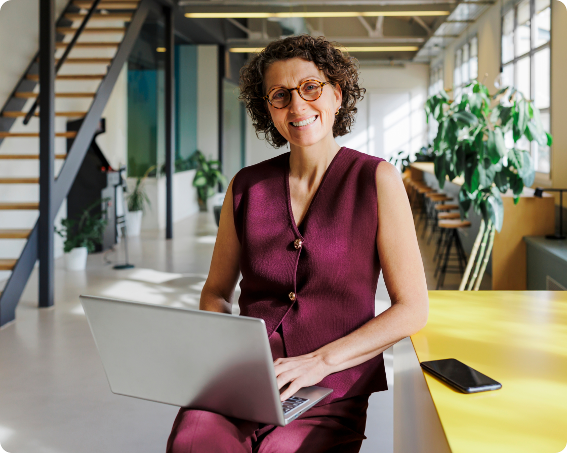 Image of a woman smiling to camera holding her laptop